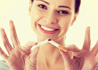 A woman breaking a cigarette in two